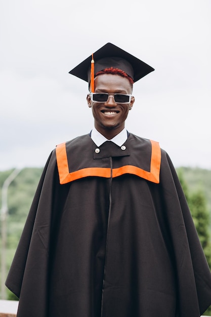 Young smiling black male on his graduation day in university Education qualification and gown concept