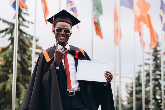 Young smiling black male on his graduation day in university Education qualification and gown concept