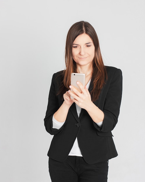 Young smiling brunette woman lady in business suit typing a mess