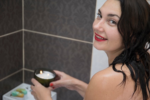 Young smiling brunette woman taking a bath with rose petals at home doing spa treatments for balance and mental health