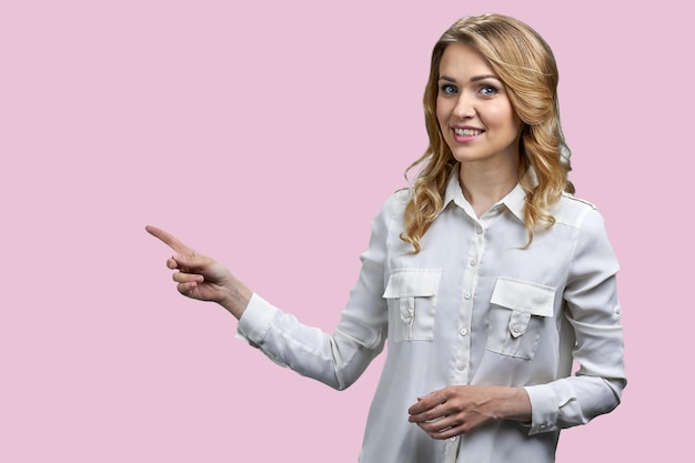 Young smiling business lady showing empty space on color background