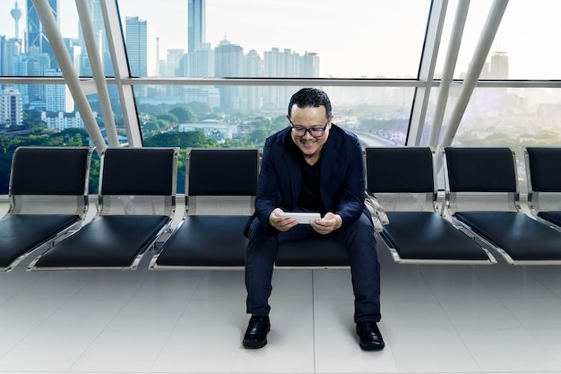 Young smiling businessman sitting at conference room and using smart phone