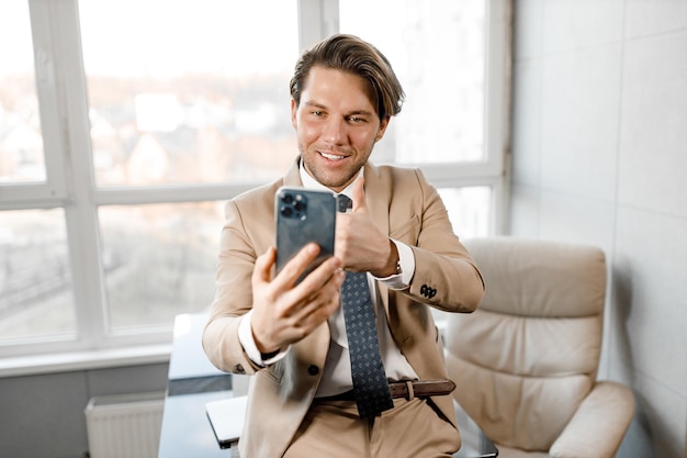 Young smiling caucasian man using smartphone working and video conference meeting at home office