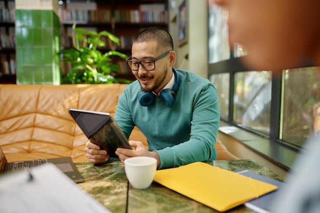 Young smiling employee using digital tablet screen coworking space