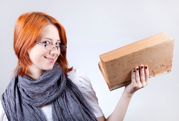 Young smiling fashion girl in glasses with age book.