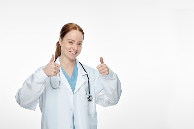 Young smiling female doctor doing thumbs up thumbs up sign. High quality photo