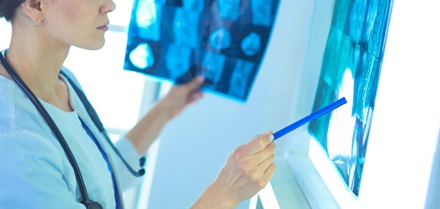 Young smiling female doctor with stethoscope pointing at Xray at doctor's office