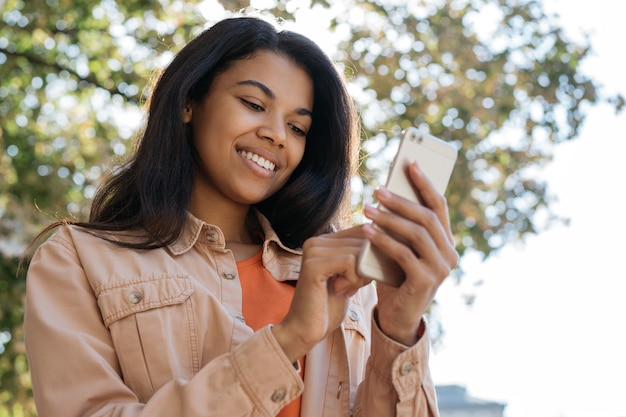 Young smiling female holding smartphone, chatting, communication, looking at digital screen