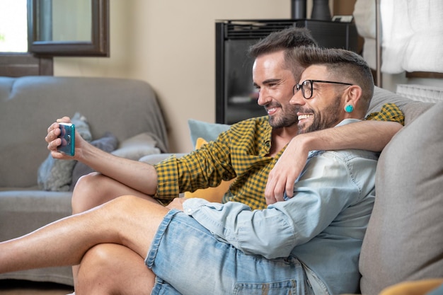 Young smiling gay couple taking selfie at home