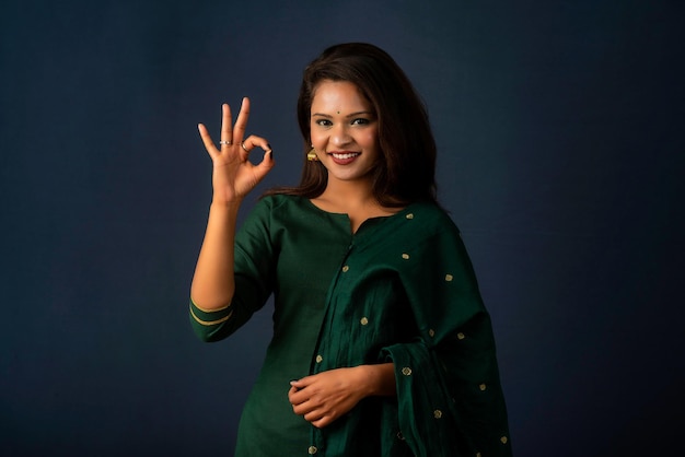 Young smiling girl showing ok sign or thumbs up on a grey background