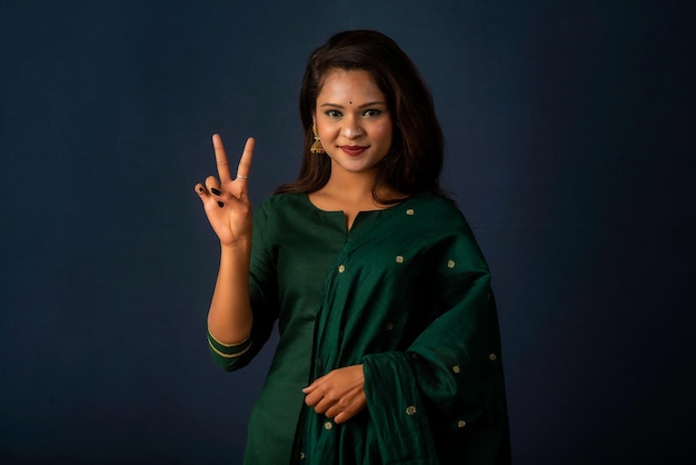 Young smiling girl showing ok sign or thumbs up on a grey background