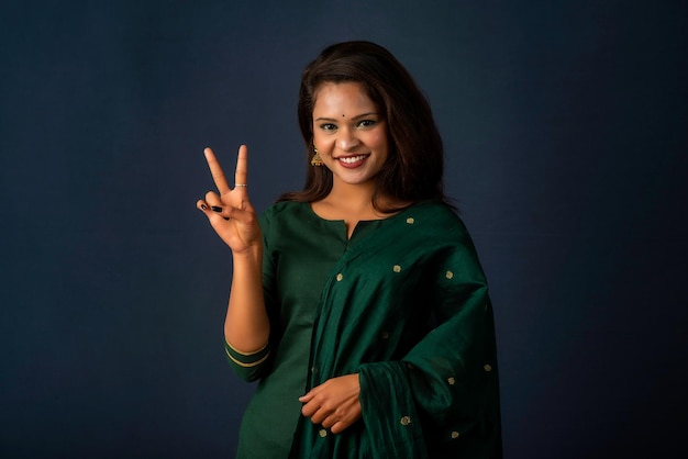 Young smiling girl showing ok sign or thumbs up on a grey background