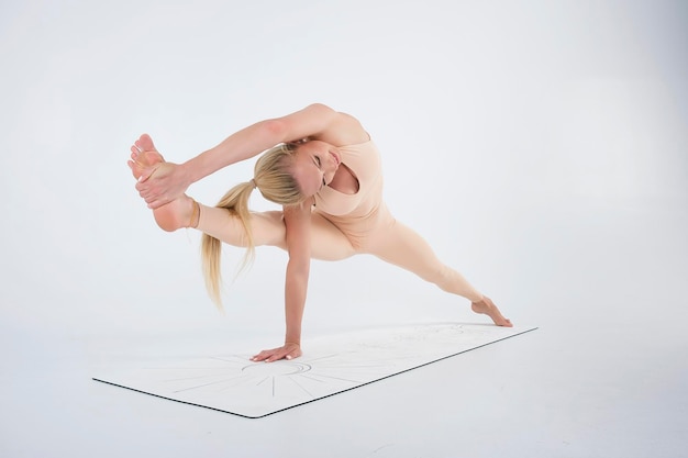 Young smiling girl shows yoga asanas in longitudinal splits standing on one hand