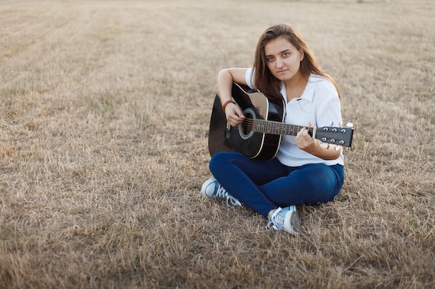 Young smiling girl singing at guitar