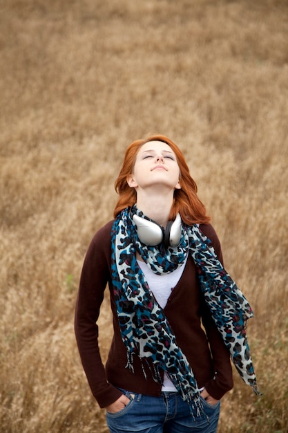 Young  smiling girl with headphones at field.