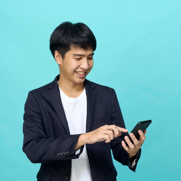 Young smiling handsome Asian man in a semiformal suit using a mobile phone