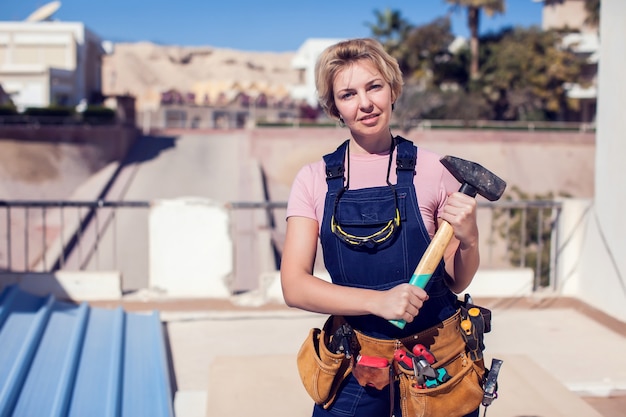 Young smiling handy woman with short blond hair working with hammer.