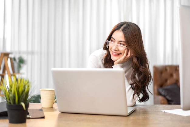 Young smiling happy beautiful asian woman relaxing using laptop computer at homeYoung creative girl working and typing on keyboardwork from home concept