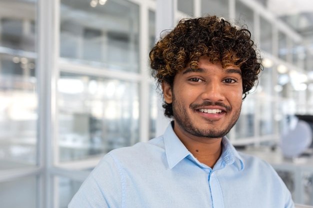 Young smiling indian programmer close up smiling and looking at camera portrait of man with curly