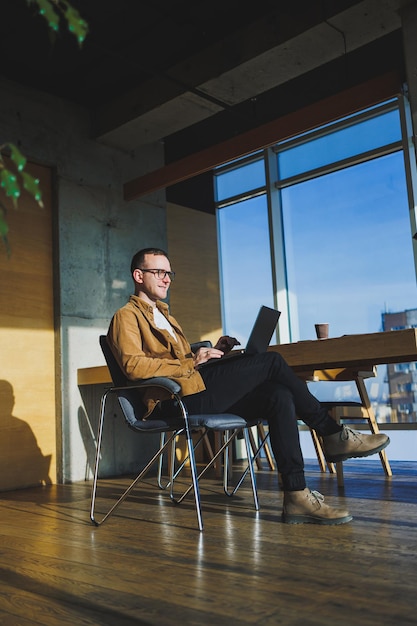 Young smiling male freelancer working remotely in a spacious modern office A manager in comfortable clothes works relaxed in the office