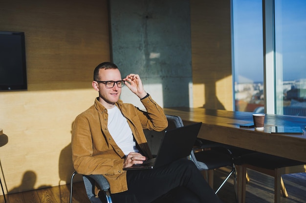 Young smiling male freelancer working remotely in a spacious modern office A manager in comfortable clothes works relaxed in the office