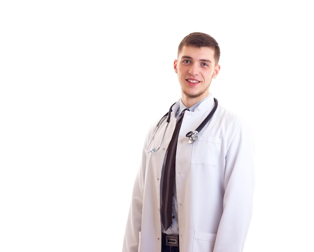 Young smiling man in doctor gown with stethoscope on his neck on white background in studio