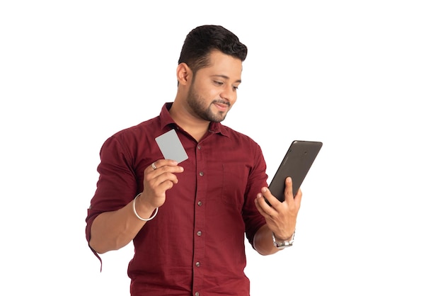 Young smiling man presenting a credit card while using a smartphone or buying online on mobile with a credit card