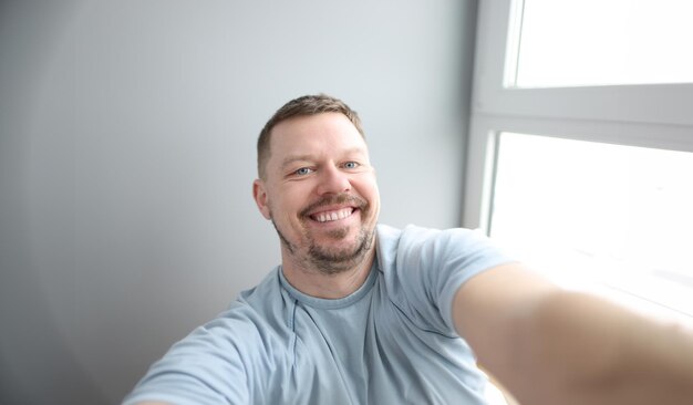 Young smiling man taking selfie at home