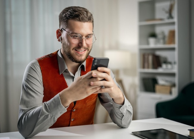 Young smiling man texting with smartphone