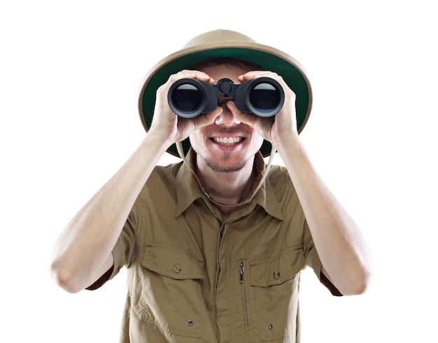 Young smiling man wearing pith helmet looking through binoculars isolated on white