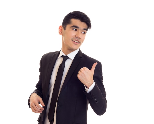 Young smiling man in white shirt and black tuxedo with black tie pointing on something