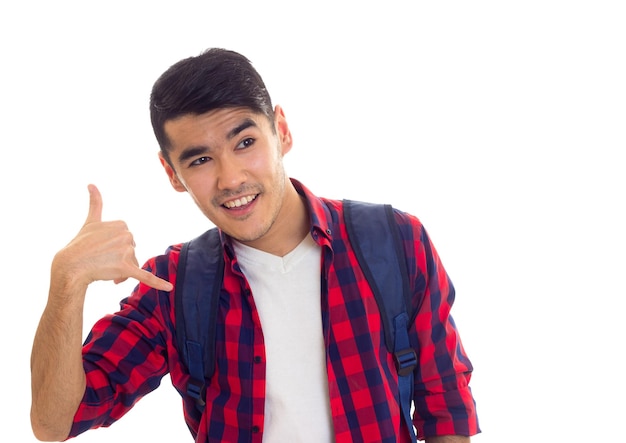 Young smiling man in white Tshirt and red checkered shirt with blue backpack showing CALL ME