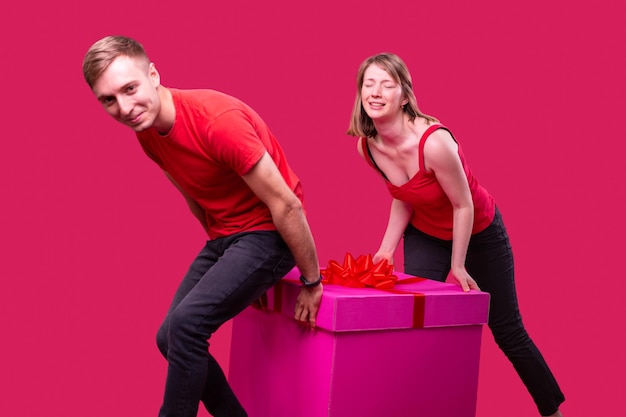 Young smiling man and woman with facial expression in red tshirts and black jeans dragging the box o...