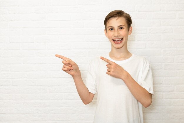 Young smiling teen boy shows his finger to the side