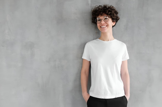 Young smiling woman in blank white tshirt looking up dreaming