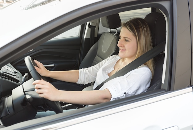 Young smiling woman driving car and looking at road