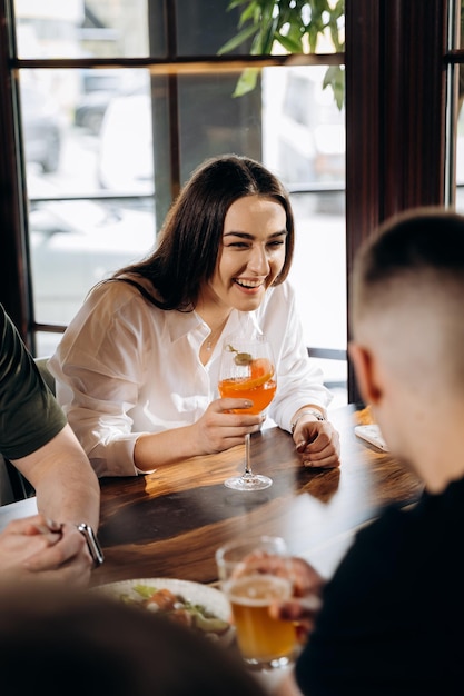 Young smiling woman enjoying a coctail in bar restaurant during rest with friends Celebration and party concept