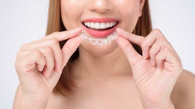 Young smiling woman holding invisalign braces in studio, dental healthcare and Orthodontic concept