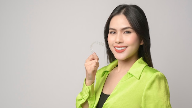 Young smiling woman holding invisalign braces in studio dental healthcare and Orthodontic conceptx9