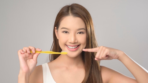 Young smiling woman holding toothbrush over white background studio