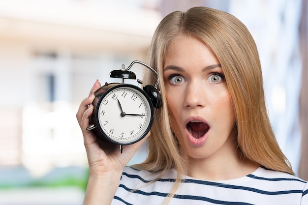 Young smiling woman holds black clock