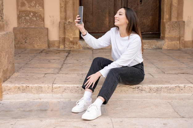 Young smiling woman of millennial generation sitting making selfie