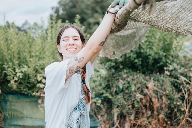 Young smiling woman resting with a big smile on her face outdoors a greenhouse after the seasonal collect of vegetables happy after a working day Funny rural collecting image