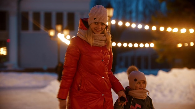 A young smiling woman skating on public ice rink with her daughter