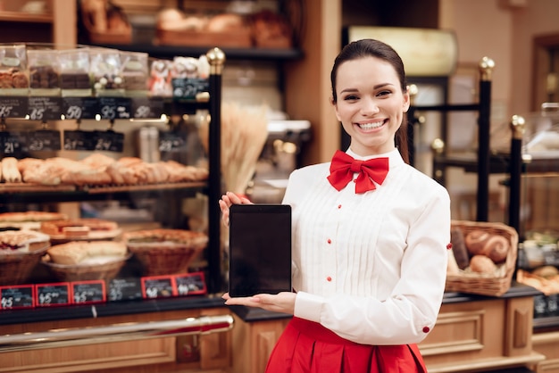 Young Smiling Woman Using Tablet in Modern Bakery.