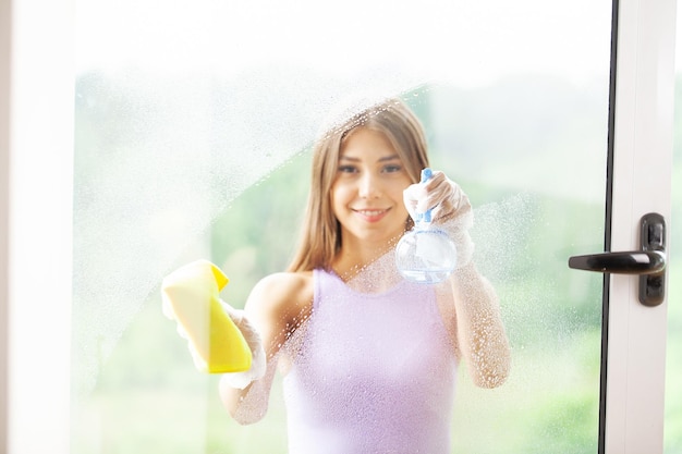 Young Smiling Woman Washing Window with Sponge