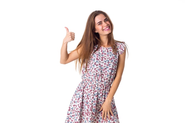 Young smiling woman wearing in white dress with varicoloured butterflies showing thumb up on white background in studio