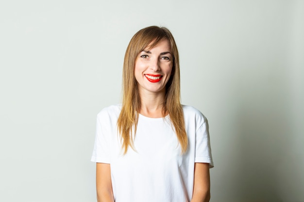 Young smiling woman in a white t-shirt on a light background