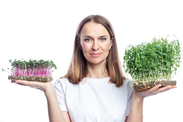 Young smiling woman in a white tank top with micro greens in her hands Health vitamins and natural food Isolated on white background