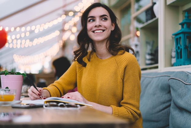 Young smiling woman with smartphone at desk with notebook